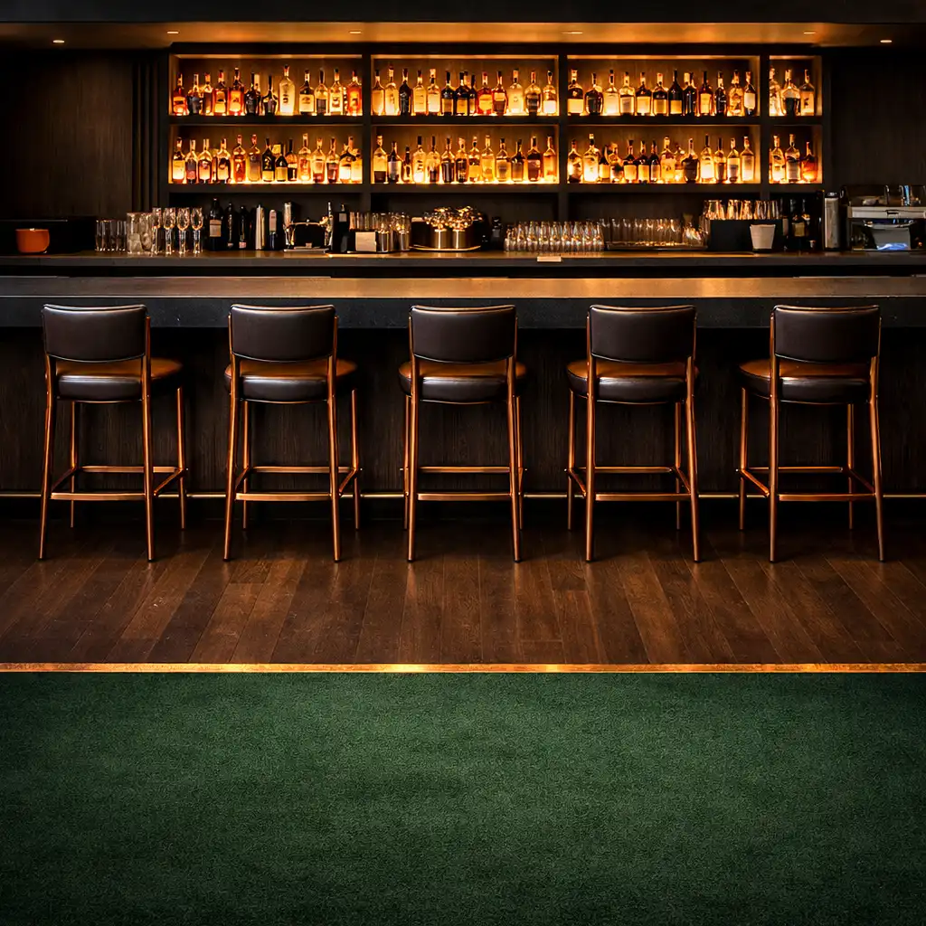 Bar with dark stone top, backlit shelves, and a flooring transition to forest green carpet